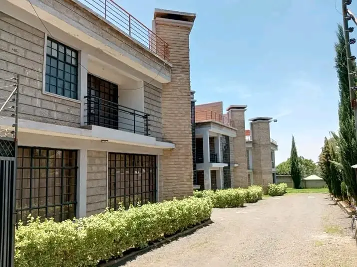 Stone apartment blocks with hedges and a drive